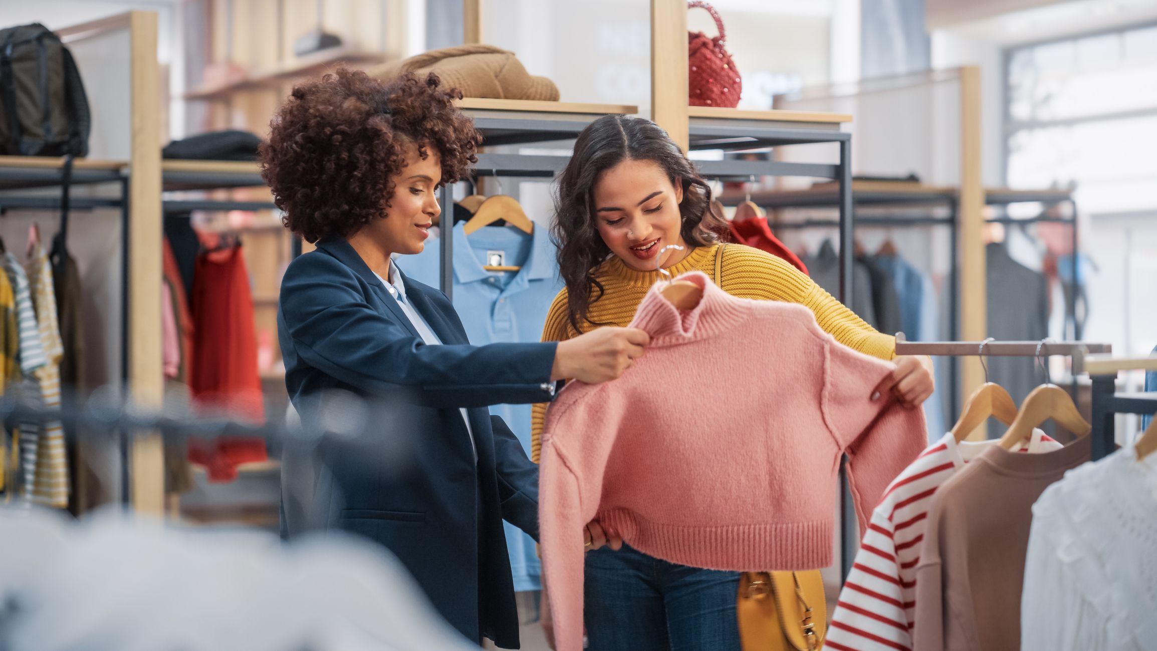 Frauen im Kleiderladen kaufen rosa Pullover